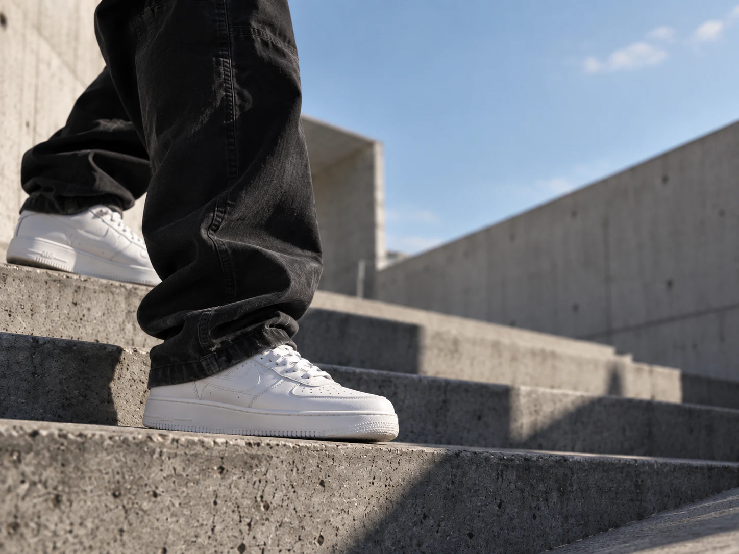 Persona con pantalón oscuro y calzado blanco en escalones de concreto